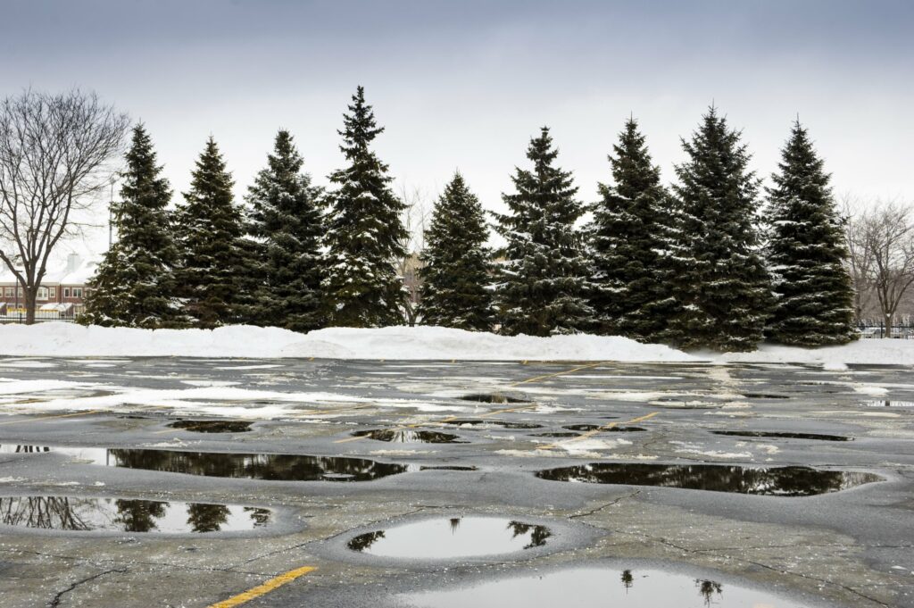 Image of wet parking lot with snow representing the need for concrete contracting in Kansas City with Mega KC